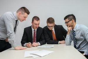 quatre hommes regardant le papier sur la table