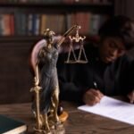 Gros plan d'une figurine de Lady Justice sur le bureau d'un avocat avec des livres et des documents.