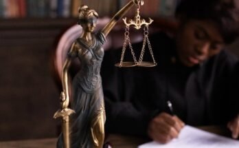 Gros plan d'une figurine de Lady Justice sur le bureau d'un avocat avec des livres et des documents.