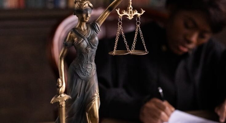 Gros plan d'une figurine de Lady Justice sur le bureau d'un avocat avec des livres et des documents.