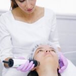 Une esthéticienne effectue un traitement de soin de la peau au laser sur un patient dans une clinique.