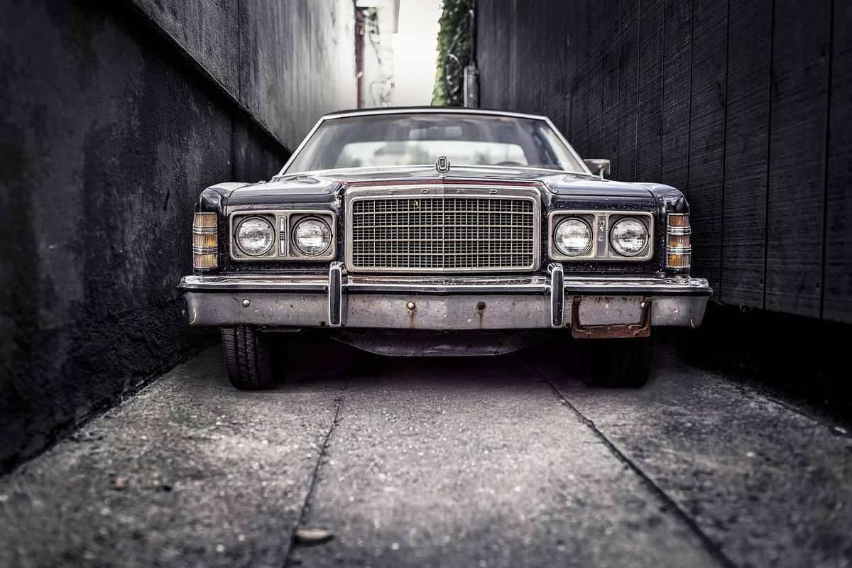 Une voiture vintage encadrée par des murs sombres dans une allée
