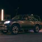 SUV noir stationné sur rue nocturne avec phares allumés