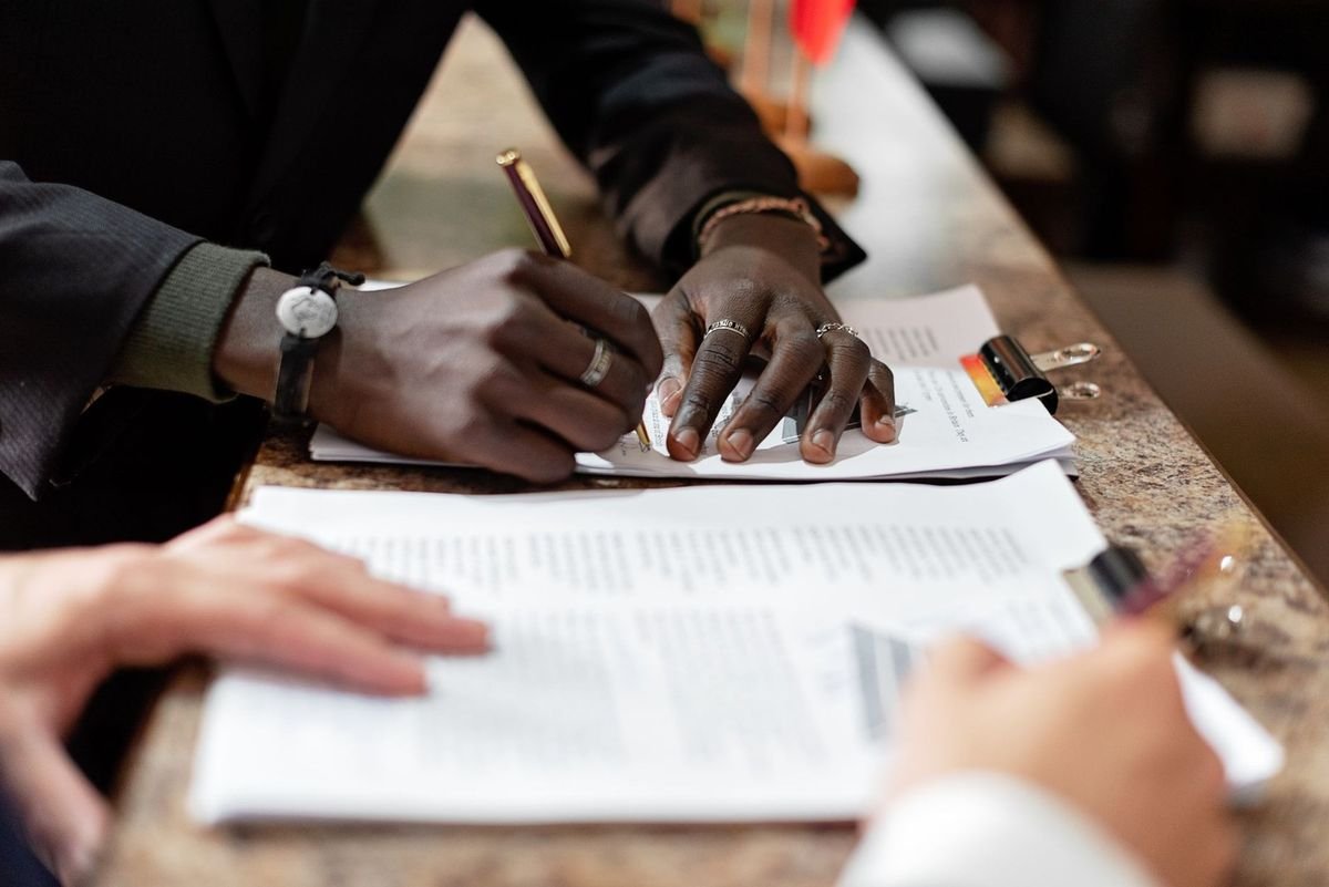 Deux mains écrivent sur des documents à une table Deux mains écrivent sur des documents à une table