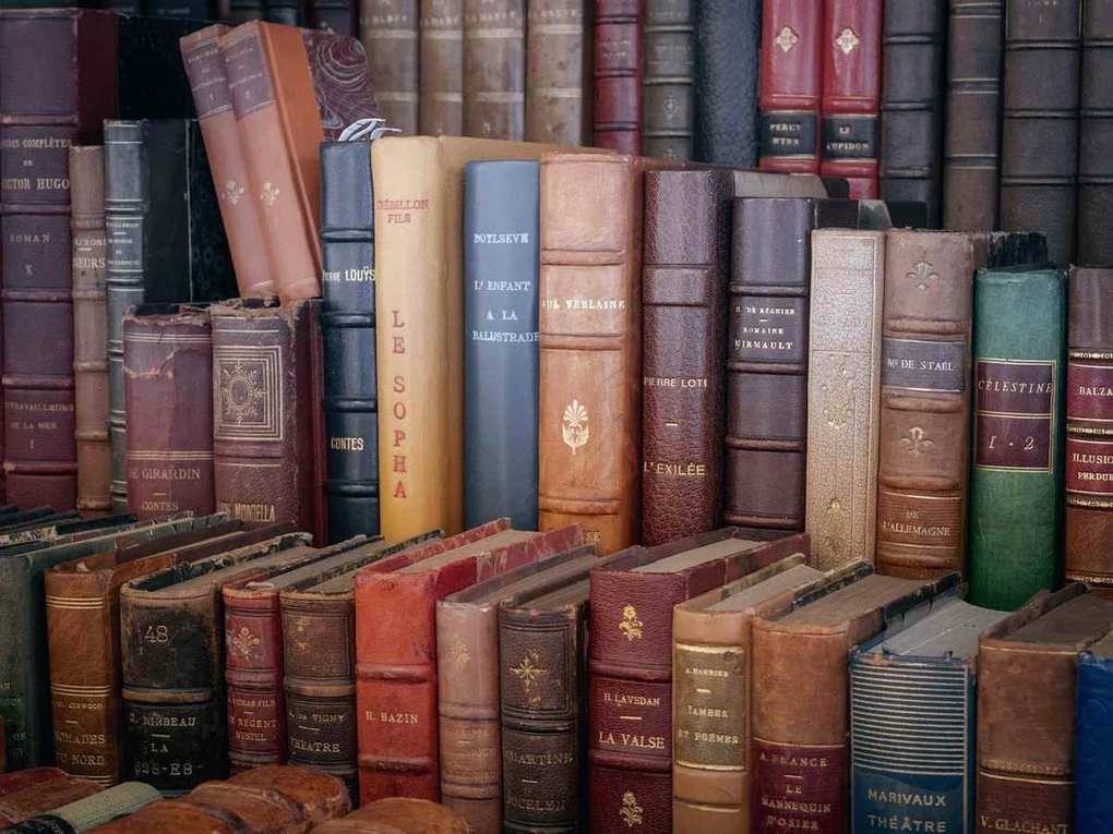 Vieux livres anciens entassés sur des étagères de bibliothèque